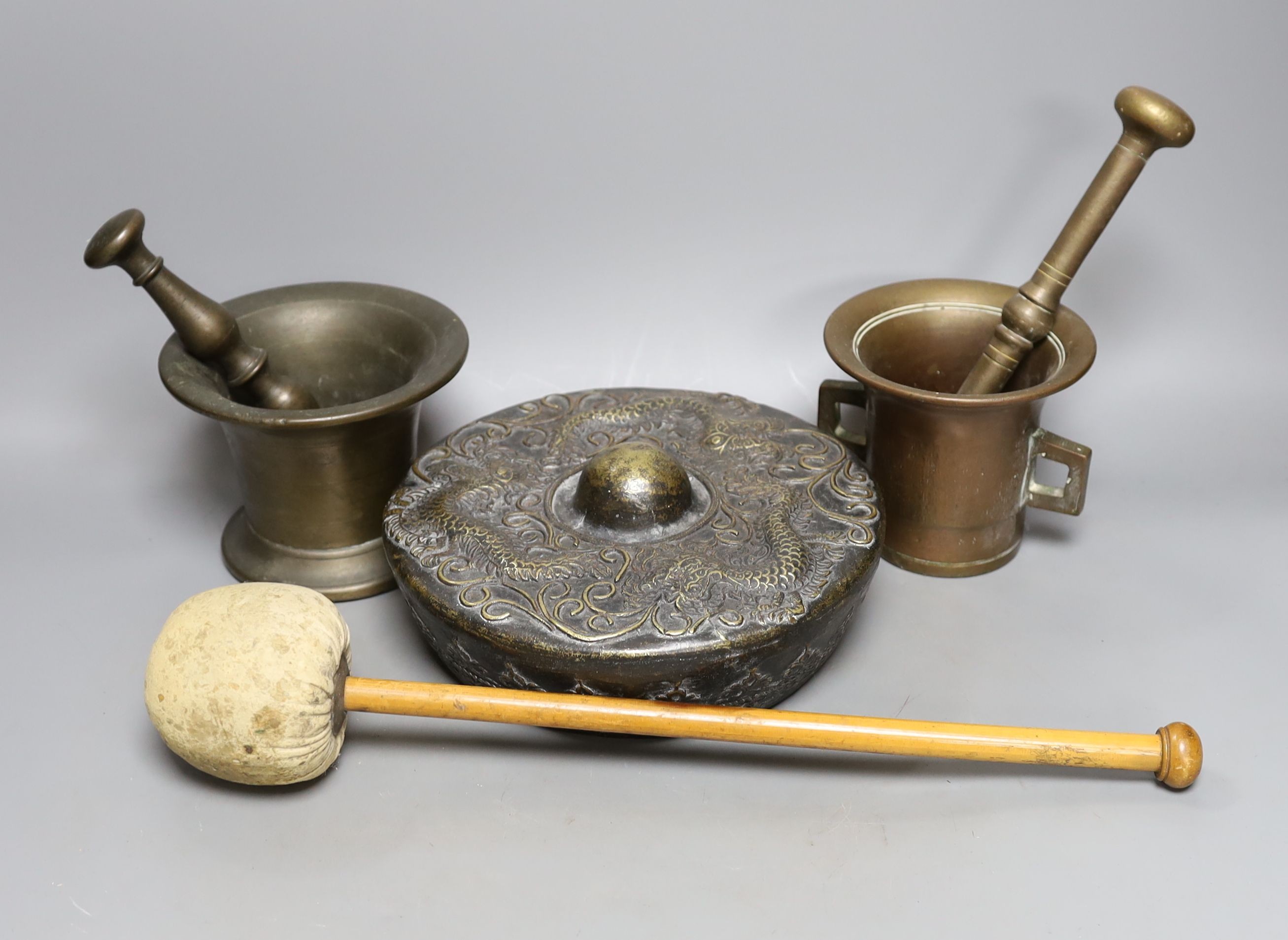 Two pestles and mortars and a Chinese gong with beater, gong 21 cms wide.